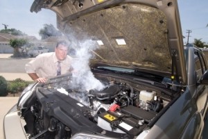 A man is very frustrated and sweaty while trying to evaluate his smoking car engine