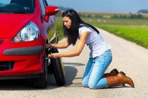 Young woman with a flat tire in car