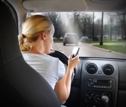 A young woman is on the cell phone textign and driving