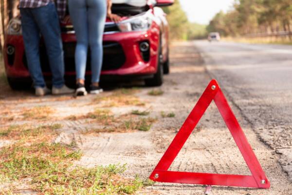 A couple stranded on the road, checking for vehicle damage signs
